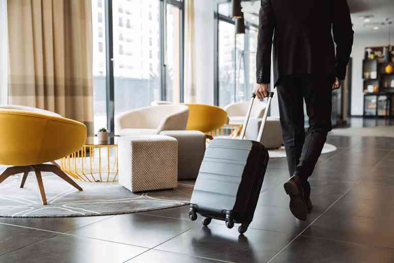 © Drobot Dean - stock.adobe.com Mann zieht Koffer in Hotellobby