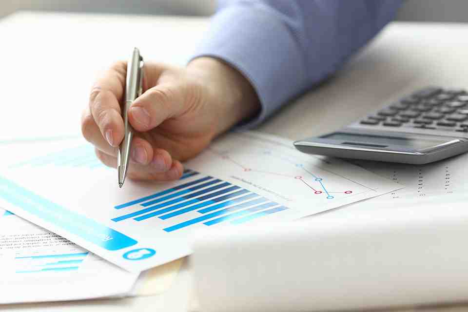 © H_Ko - stock.adobe.com Diagramme, Taschenrechner und Hand mit Stift