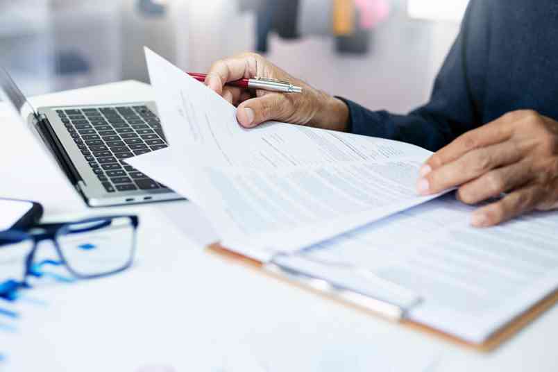 © stock.metket.com - stock.adobe.com Person mit Dokumenten und Laptop