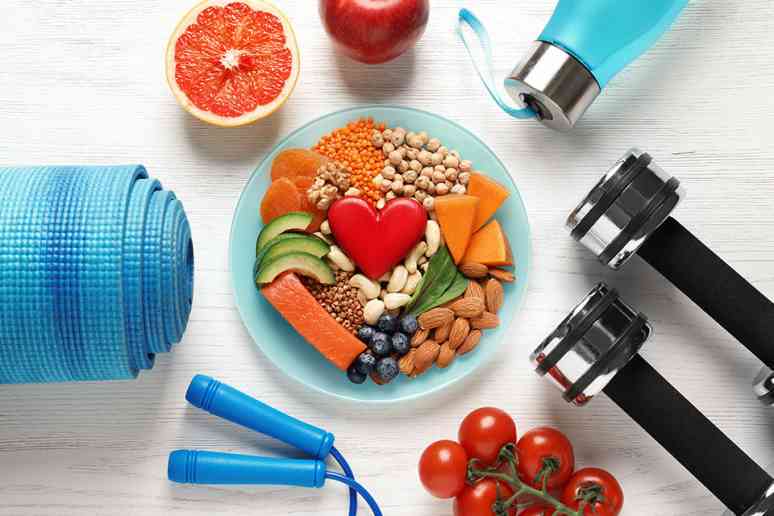© New Africa - stock.adobe.com Bowl mit Obst darum angeordnet liegen Fitnessgeräte