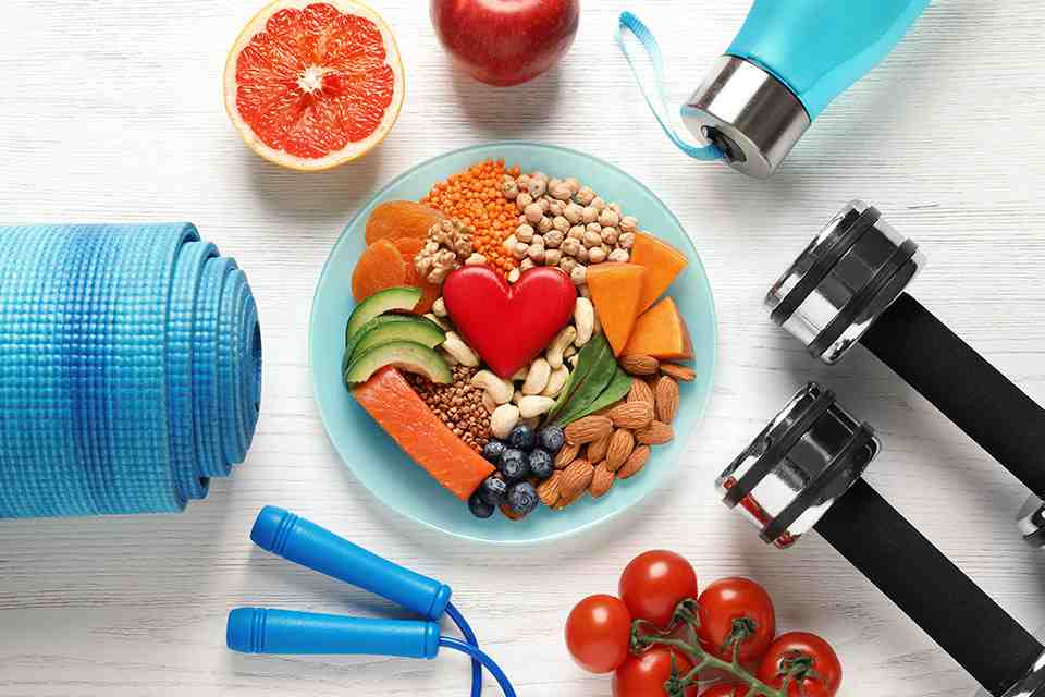© New Africa - stock.adobe.com Bowl mit Obst darum angeordnet liegen Fitnessgeräte