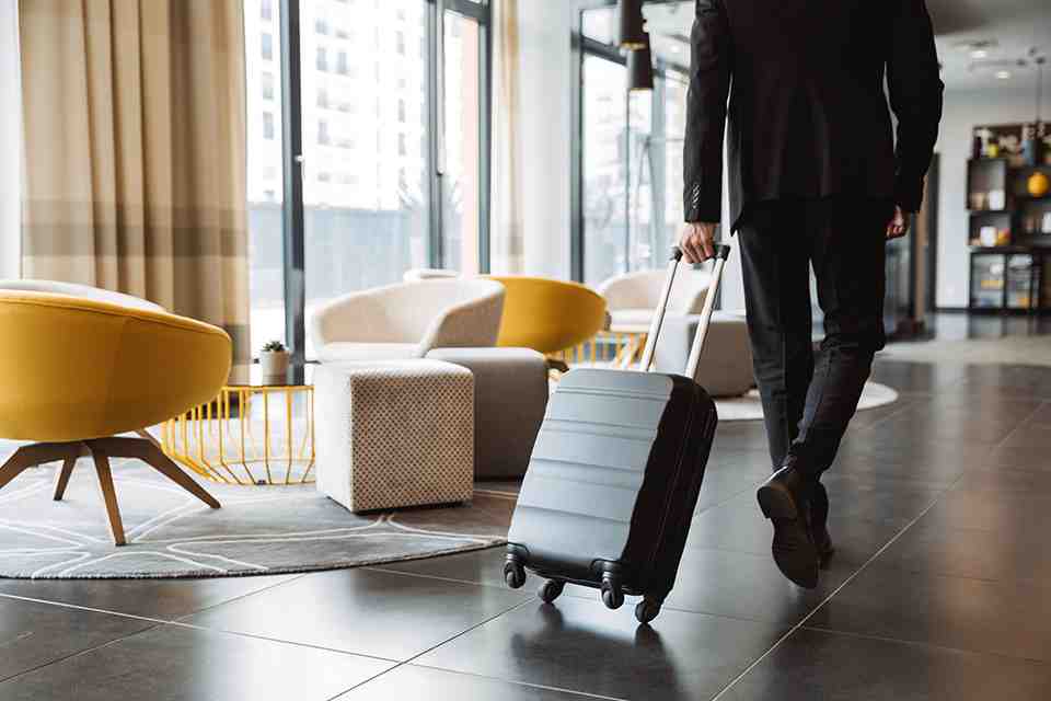 © Drobot Dean - stock.adobe.com Mann zieht Koffer in Hotellobby