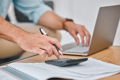 Männerhände auf PC und Taschenrechner