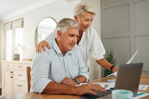 Zwei Pensionisten beim Esstisch mit einem Laptop