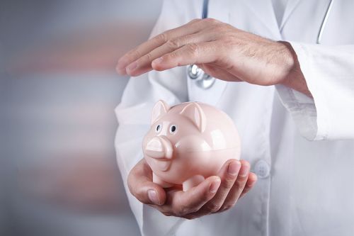 Arzt hält Hand über Sparschwein