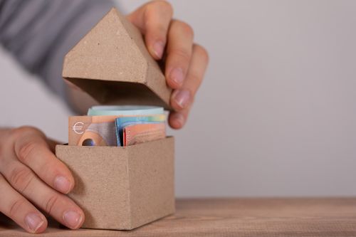 Schachtel in Hausform mit Geldscheinen