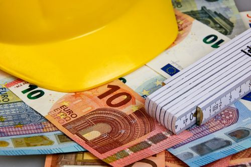 Bauhelm, Zollstock und Geldscheine