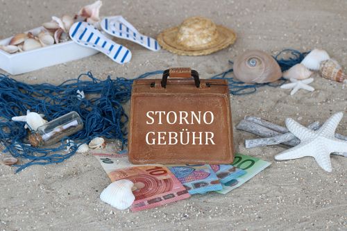 Sand, Muscheln, Geldscheine und Koffer mit Aufschrift Stornogebühr