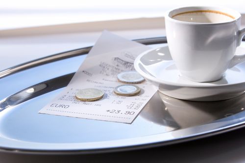 Trinkgeld auf Tablett mit leerer Kaffeetasse
